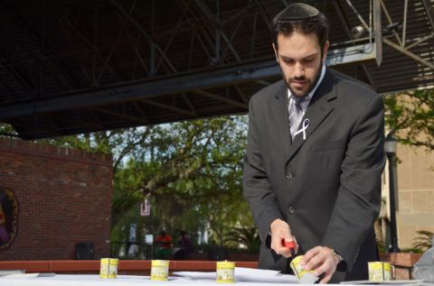 Rabbi Daniel Wolnerman, of UF Hillel, lights a candle at a memorial ceremony commemorating genocide victims on Bo Diddley Community Plaza on Sunday. April is Genocide Awareness Month. Photo courtesy Tony Sadiku, Alligator